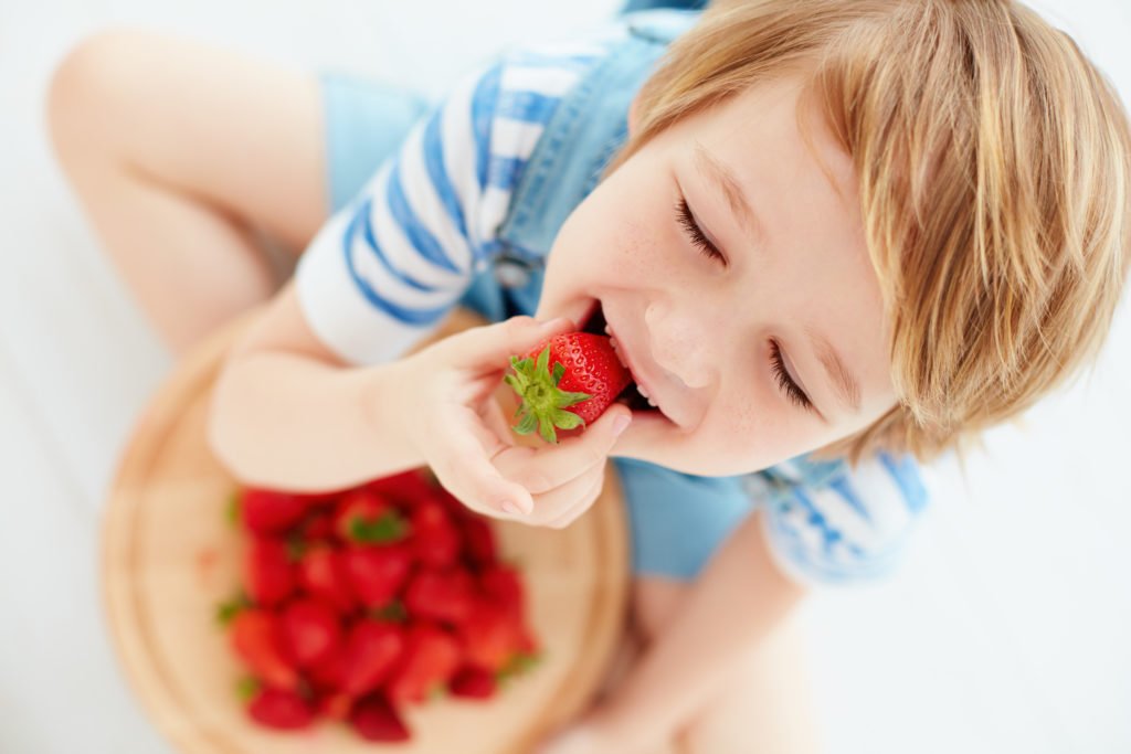 un enfant mange des fraises avec plaisir