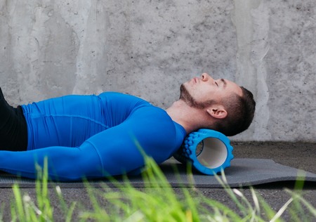 Homme avec un rouleau de massage sous la nuque